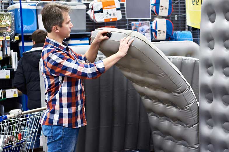 Man Choosing an Air Mattress at a Store