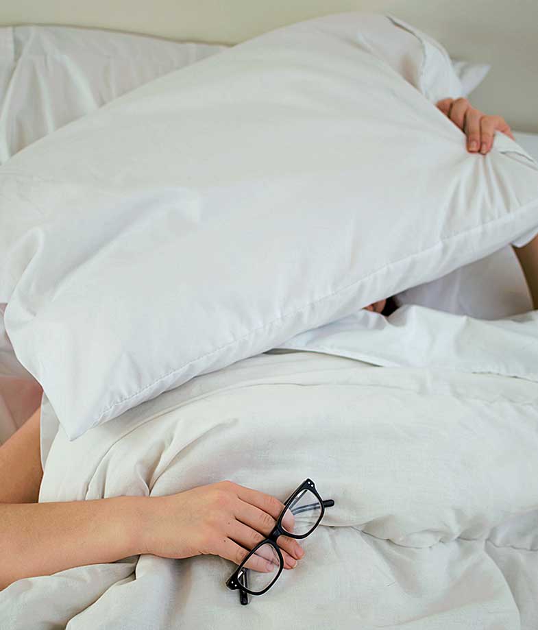 Person in Bed Blocking Face with Pillow
